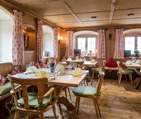 View from the entrance to the cosy farmhouse parlour in the Hotel Der Westerhof coffered ceiling and old wooden floor wooden tables wooden chairs old windows view of the lake